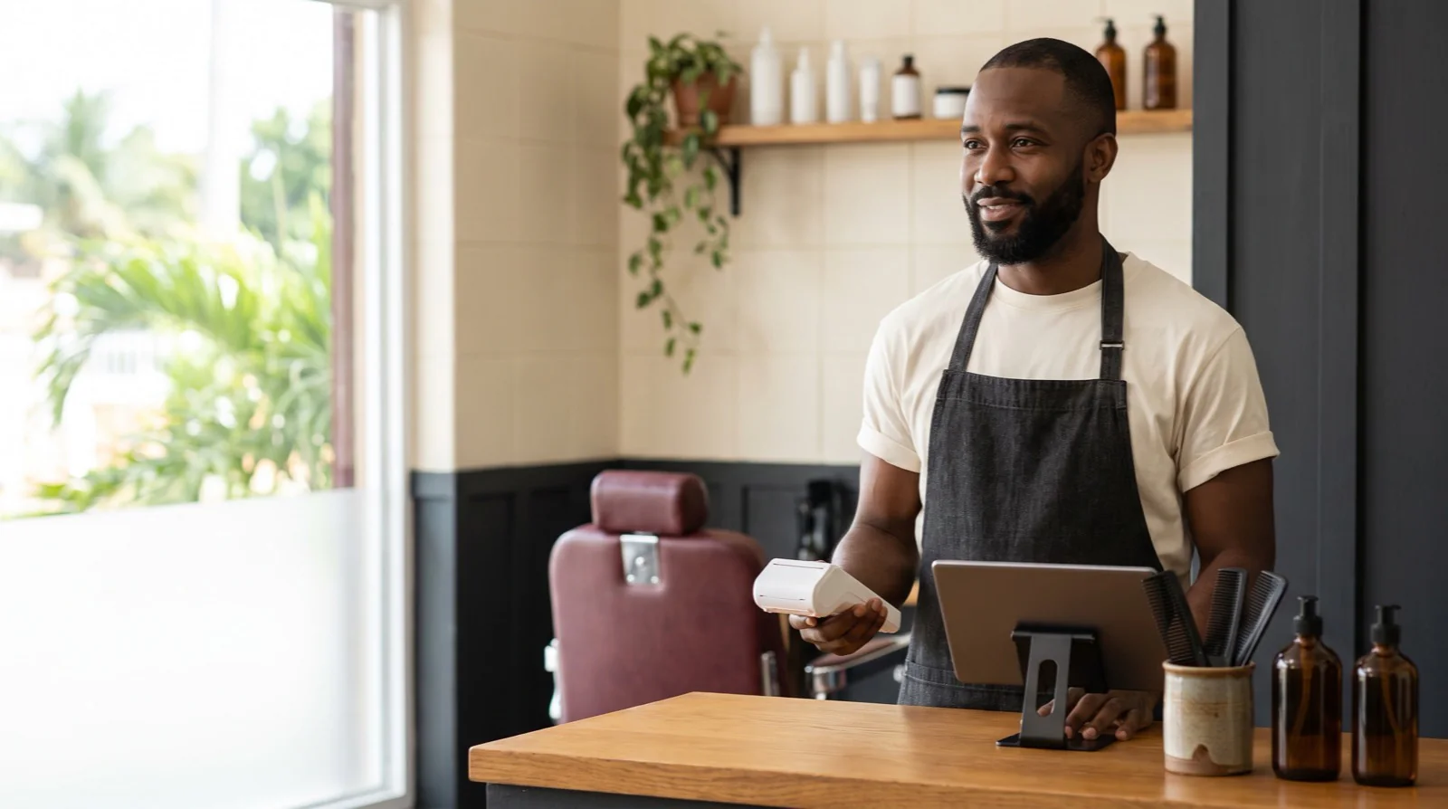 Barbershop owner taking a card payment at his front counter, selling on his Wix store — Paperless Blueprint Wix payment gateway integration in Jamaica